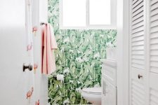 a small tropicla bathroom with a tropical leaf wallpaper wall, white appliances and a flamingo print shower curtain