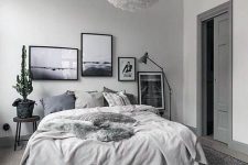 a soothing grey bedroom with a dramatic gallery wall, grey and blue bedding, a fluffy pendant lamp