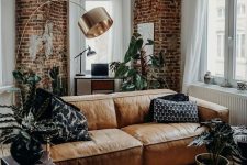 a stylish contemporary and industrial living room accented with red bricks and an amber leather couch