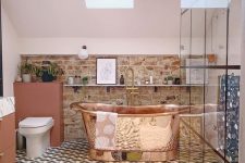 a stylish eclectic bathroom with a mosaic tile floor, a brick wall, skylights and a copper bathtub that is a centerpiece here