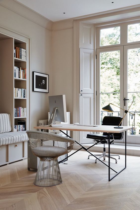 a stylish eclectic home office in neutrals with a built-in bench and shelves, a desk and catchy chairs and an entrance to the balcony