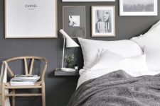 a stylish grey bedroom with graphite grey walls, a gorgeous gallery wall, white and grey bedding and touches of light colored wood