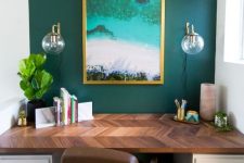 a stylish home office with a hunter green accent wall, a bright artwork, a stylish desk with a patterned tabletop