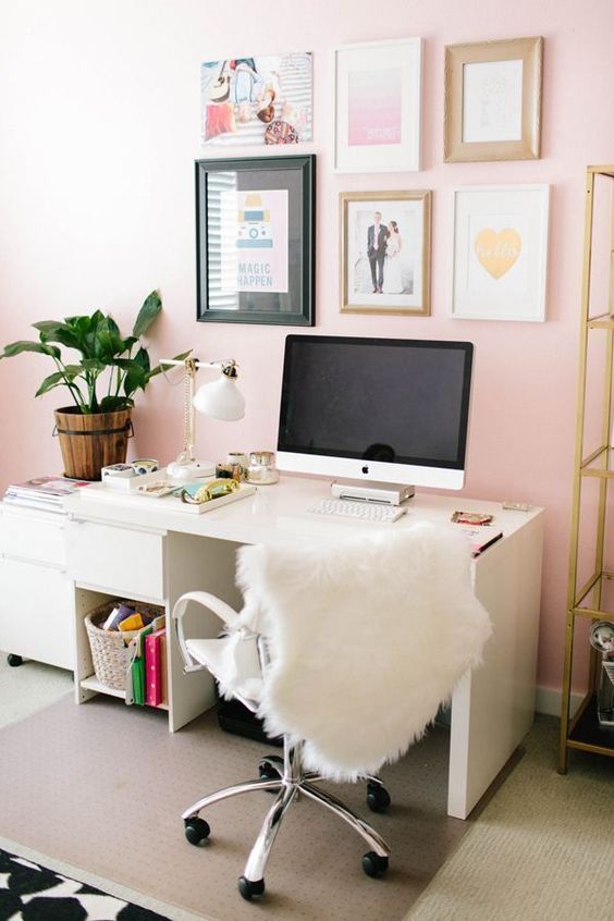 a stylish modern home office with light pink walls, neutral furniture, a glam gallery wall, gold touches for a chic feel