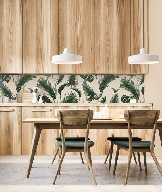 a stylish modern kitchen with sleek wooden cabinets, a tropical leaf backsplash and green chairs that echo with it