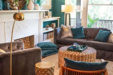 a stylish tropical living room with emerald walls, grey furniture, teal pillows, rattan elements and tropical leaves