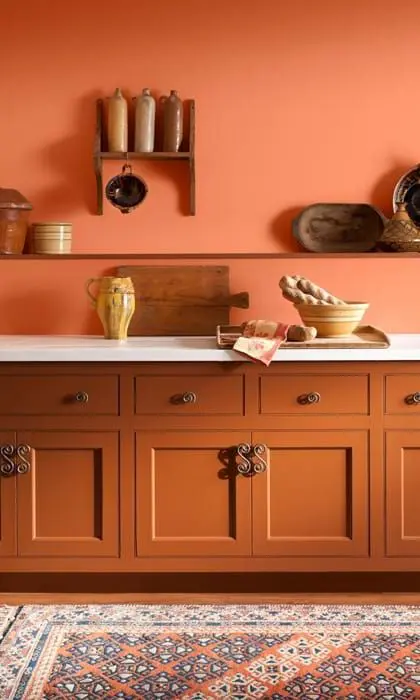a terra cotta kitchen with burnt orange walls and white stone countertops is a stylish and chic space