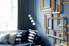 a unique living room with a bright blue floor, grey walls, a black sofa, monochromatic pillows and gold frames on the wall