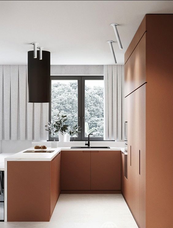 a very chic minimalist matte terra cotta kitchen with white stone countertops and a black hood and fixtures is wow