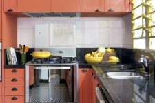 a vibrant kitchen with burnt orange cabinets, a mosaic tile floor, black countertops and a white tile backsplash