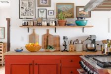 a vintage farmhouse kitchen in neutrals but with burnt orange cabinets, light stained countertops and a pretty gallery wall