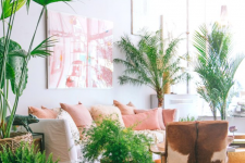 a welcoming and airy living room with a white sofa and pink pillows, a cowhide chair, a boho rug, a pink gallery wall and potted plants