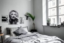 a welcoming dove grey bedroom with grey walls, a black and white gallery wall, grey bedding and a lamp plus greenery