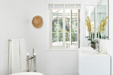 a white beach bathroom with an oval tub, a floating vanity, a couple of mirrors, a cool tiled floor and a hat