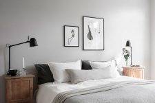 an airy dove grey bedroom with wooden nightstands, black lamps, a black and white gallery wall and grey bedding