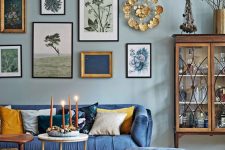 an eclectic living room with light blue walls, a bold blue sofa and a matching ottoman, a gallery wall and a crystal chandelier