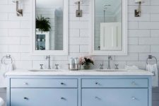 an ethereal coastal bathroom with white and marble hex tiles, a powder blue vanity, a white stone coutnertop and mirrors