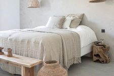 an ethereal dove grey bedroom with wicker lamps and a woven bottle, a wooden bench and nightstands and grey and white bedding