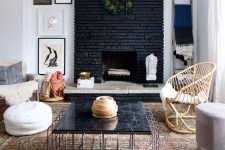 03 an eclectic living room with a black brick fireplace, stone and a greenery wreath and a black marble table that echoes with it