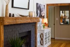 05 a stylish black brick fireplace with a rough wood mantel and frame, with some decor is a bold decor feature