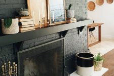 09 a black brick fireplace with white tiles in front of it, a black mantel with books and artworks for stylish monochromatic decor