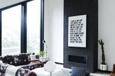 13 a laconic black brick fireplace with a graphic artwork to finish off a monochromatic look and a floral sofa to spruce up the space