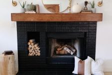14 a stylish black brick fireplace with a built-in firewood niche, a stained mantel with elegant decor is a gorgeous idea to try