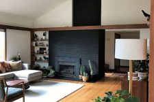 15 a statement black brick with a built-in hearth, potted cacti and succulents and a very high positioned wooden mantel