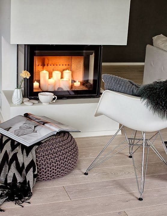 a Scandinavian space with a built-in fireplace with pillar candles inside is a creative adn cozy nook