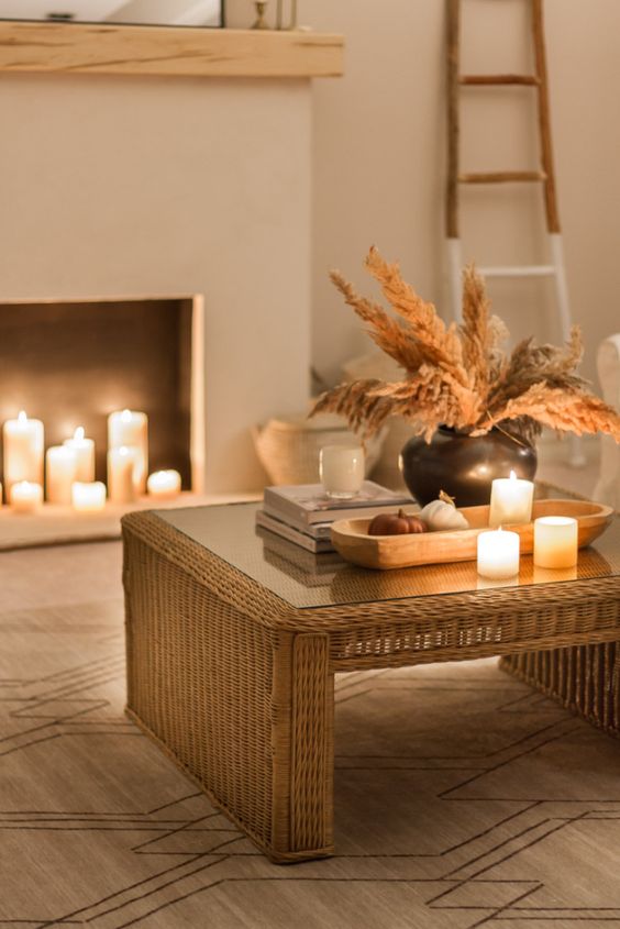 a boho space with a faux fireplace with candles, a woven table with candles and boho fall decor is cozy and inviting