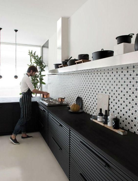 a bold contrasting kitchen with black metal cabinets, white open shelving and black and white penny tile backsplash