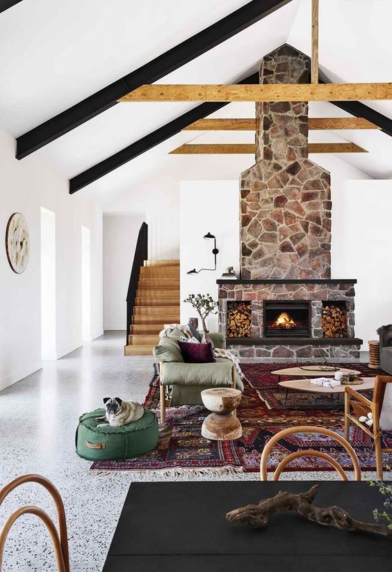 a bright boho meets rustic living room with a stone fireplace, a green and grey sofa, coffee tables and rattan furniture