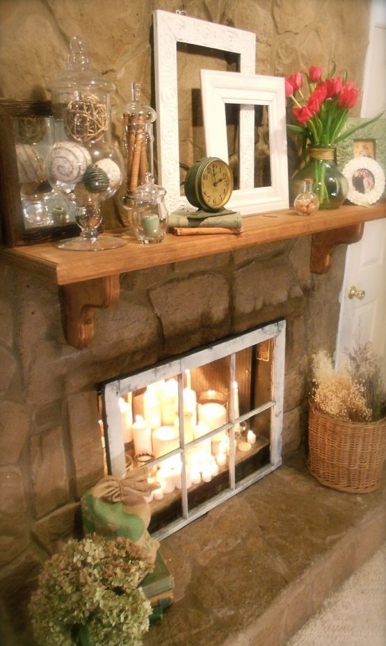a candle arrangement of different candles placed in the fireplace and a vintage window covering it