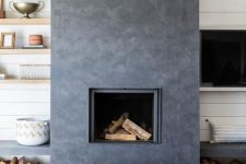 a catchy dark concrete fireplace with woven stools and benches with firewood under them is very cozy