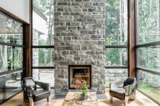 a chic contemporary living room with a stone fireplace as a centerpiece, black leather chairs and a wood slab table