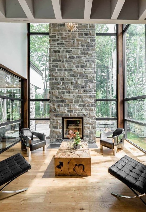 a chic contemporary living room with a stone fireplace as a centerpiece, black leather chairs and a wood slab table