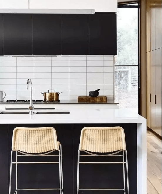 a contrasting contemporary kitchen with black cabinets, white stone countertops and a white stacked tile backsplash