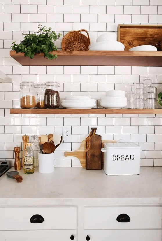 a cozy farmhouse kitchen done with white subway tiles with black grout and nautral wooden shelves