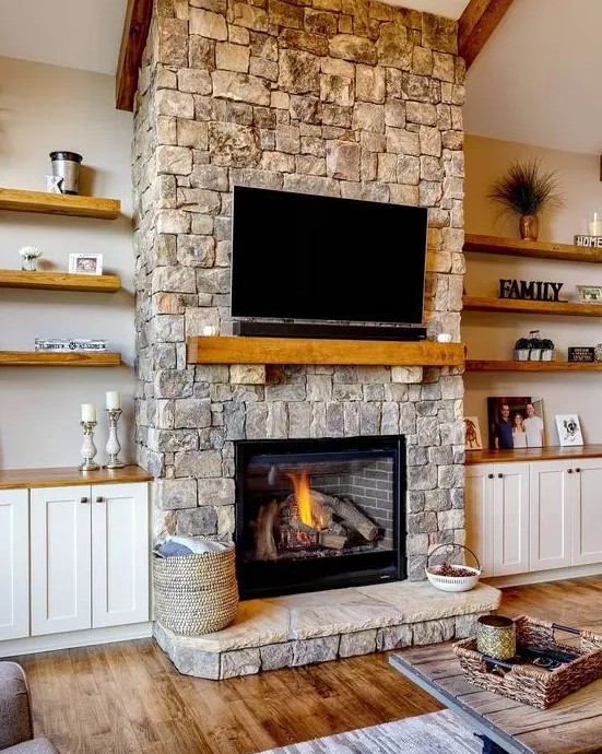 a cozy neutral living room spruced up with a stone fireplace, a wooden mantel and a TV over the fireplace