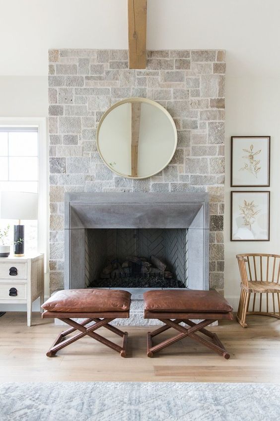 a farmhouse living room with a stone fireplace, leather stools, artwork and some farmhouse furniture is amazing
