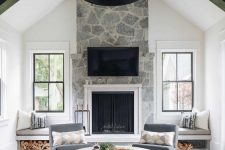 a farmhouse living room with a stone fireplace, windowsill benches and storage, an amber sofa and neutral poufs