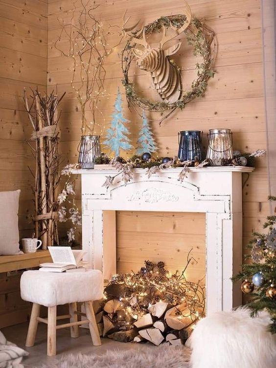a faux fireplace with logs and lights, with Christmas decor on the mantel and around it is a gorgeous idea