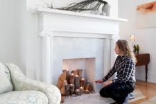a fireplace with a marble touch and thick tree branches, pebbles and tealights for a natural feel