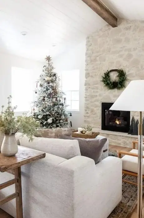 a gorgeous whitewashed stone fireplace with a wreath over it takes over the whole space and looks chic