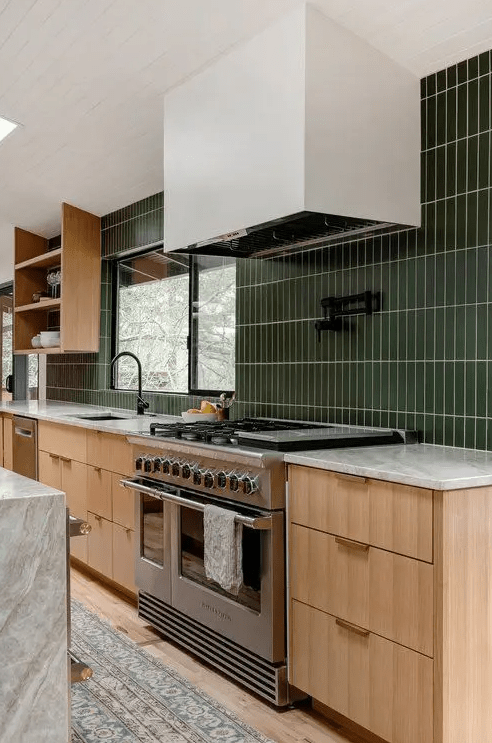 A mid century modern kitchen with stained cabinets, a green stacked tile backsplash and black fixtures