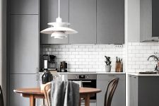 a minimalist grey kitchen with white countertops and white subway tiles plus a wooden dining set is very welcoming