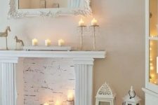 a modern candelabra on the mantel and tree stumps with candles in the fireplace