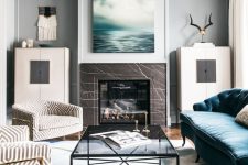 a modern chic living room with a fireplace clad with brown marble, with a glass table and a blue sofa is dreamy