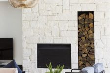 a modern coastal living room with an oversized white stone fireplace, a niche for firewood for a more welcoming feel