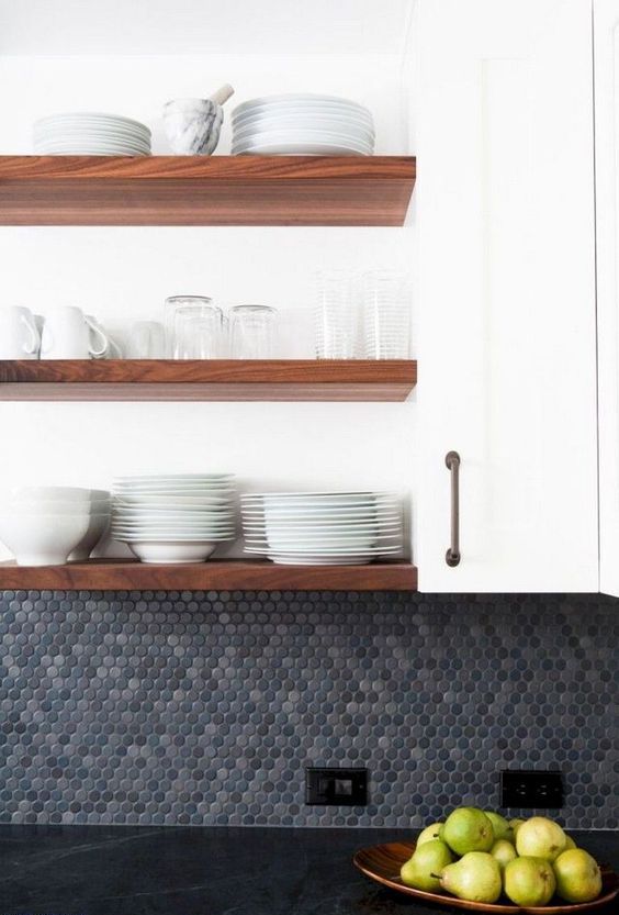 a modern farmhouse kitchen with white cabinets, a grey penny tile backsplash and a black stone countertops is chic